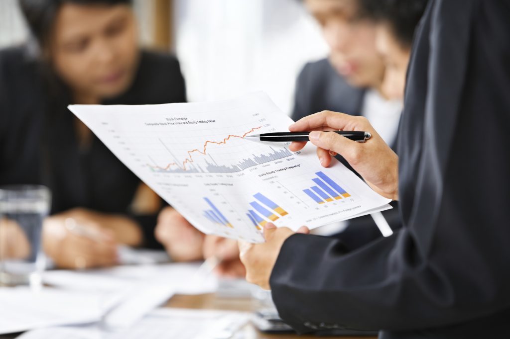 Businesswoman examining graphs with other working people on background